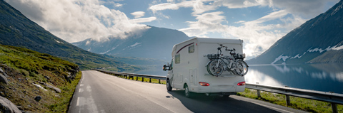 RV driving on a mountain road in the sun.